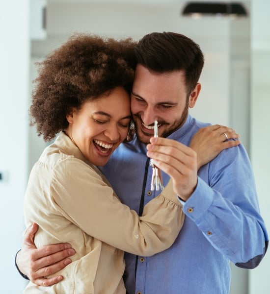 Man and woman excitedly hold keys to their house