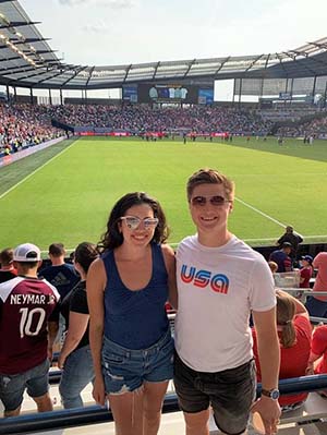 Heath Snider standing in soccer stadium seats with female partner