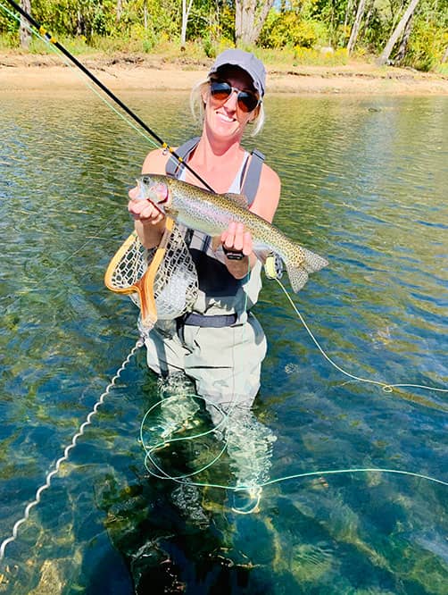 Whitney in fly fishing gear holding fish